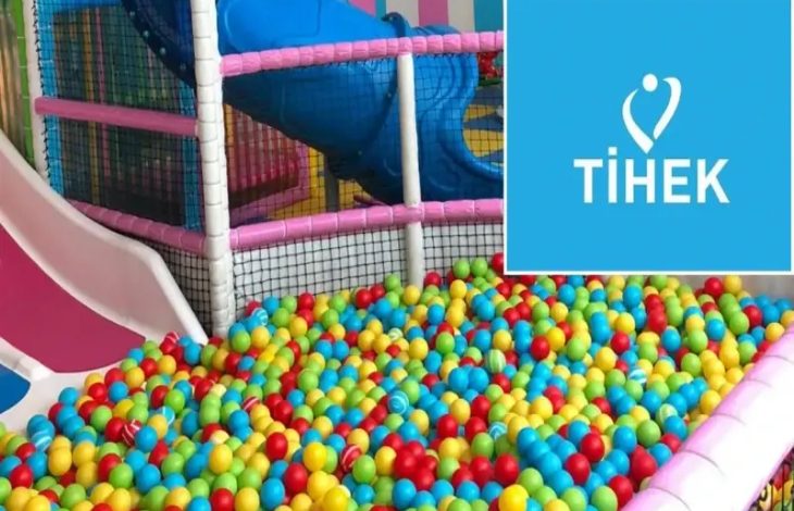 Rengârenk toplarla dolu bir çocuk oyun havuzu ve kaydıraklı bir oyun alanı görülüyor. Sağ üst köşede mavi zeminde “TİHEK” logosu yer alıyor. Görsel, bir çocuk oyun alanı ile kurum logosunun birlikte sunulduğu bir haber görseli niteliğinde.