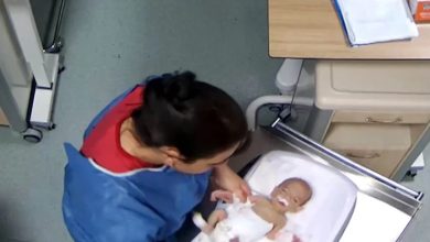 Hemşirenin küvöz içinde bulunan bebeğin yanında dururken çekilmiş görüntü.