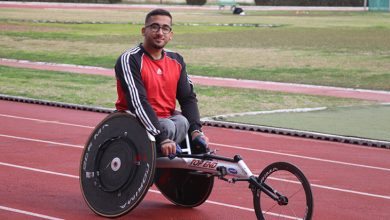 Bedensel engelli sporcu Umut Çabuk üç tekerlekli atletizm aracıyla tartan pistte poz veriyor.