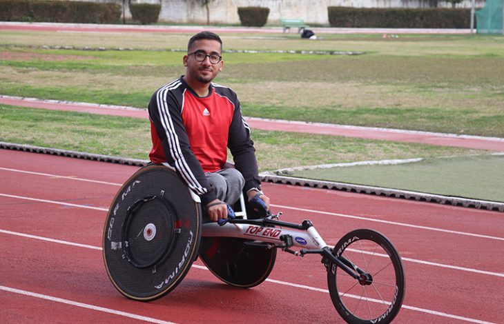 Bedensel engelli sporcu Umut Çabuk üç tekerlekli atletizm aracıyla tartan pistte poz veriyor.