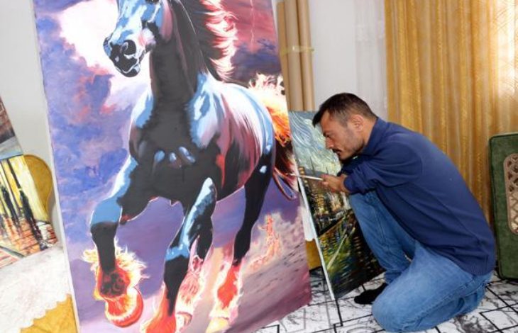 Ressam Vedat Kiyat, dizlerinin üstünde oturarak dirseğiyle koşan at eseri çiziyor.