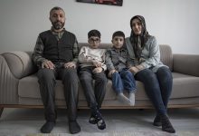 Gri tonlu bir salonda, bir kanepeye yan yana oturmuş dört kişilik bir aile. Anne ve baba iki yanda, aralarında iki çocuk; hepsi kameraya sakin, ciddi ve biraz yorgun bakıyor. Oda sade, sessiz ve durağan bir anın içine sıkışmış gibi.