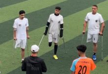 Beyaz formalı üç ampute futbolcu sahaga, karşılarında hocaları ve turuncu formalı sporcu bulunuyor.