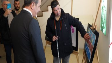 Görme engelli ressam İlker Ertuğrul Braille eserine eliyle dokunuyor ve Beyoğlu Belediyesi Başkan Vekili Sefer Karaahmetoğlu yanında bulunuyor.