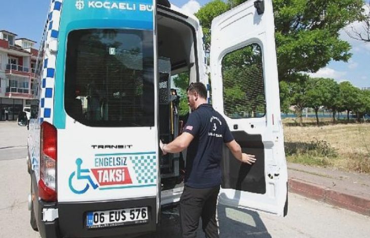 Bir minibüs tipi “Engelsiz Taksi”nin arka kapısı açık; görevli araçtan inip binmeye yardımcı oluyor. Belediye logosu ve tekerlekli sandalye simgesiyle, erişilebilir ulaşım hizmeti vurgulanıyor.