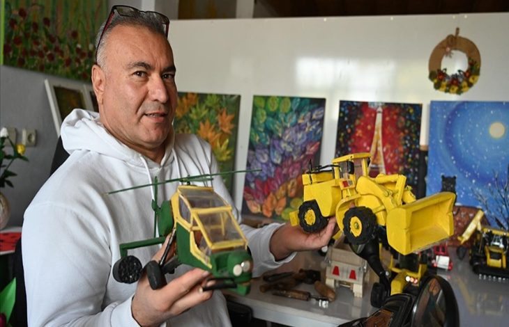 Beyaz kapüşonlu bir adam, atölye gibi düzenlenmiş bir odada elinde ahşaptan yapılmış yeşil bir helikopter ve sarı bir iş makinesi maketi tutarak kameraya gösteriyor. Arka planda renkli tablolar ve küçük oyuncaklar, emeğin ve sabrın kokusu havada asılı.