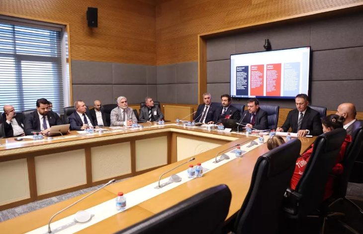 Bir toplantı salonunda uzun masa etrafında toplanan komisyon üyeleri ve davetliler, engelli bireylerin sporla ilgili sorunlarını görüşürken görülüyor.