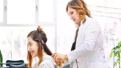 Aydınlık bir salonda, beyaz önlüklü bir kuaför kadının genç bir kadının saçını şekillendirdiği görülüyor. Genç kadın gülümseyerek aynaya doğru bakıyor; kuaför ise dikkatle saçına toka yerleştiriyor. Büyük pencerelerden gün ışığı süzülüyor, ortam ferah ve umutlu.