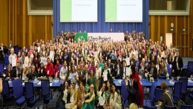 Büyük bir konferans salonunda yüzlerce kişinin yer aldığı toplu bir hatıra fotoğrafı çekilmiş. Arkada “Zero Project Conference” yazılı büyük ekranlar bulunuyor. Katılımcılar sahne önünde ve salon içinde bir araya gelmiş; bazıları sertifika ya da plaket tutuyor. Uluslararası ve kapsayıcı bir etkinliğin coşkulu final karesi gibi görünüyor.