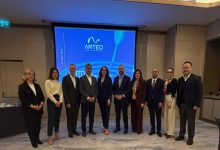 Görselde, bir toplantı salonunda yan yana dizilmiş şekilde poz veren dokuz kişilik bir grup görülüyor. Arkada büyük ekranda ARTED logosu ve toplantıya ait sunum yansıtılmış. Kişiler resmi kıyafetleriyle, toplantı veya genel kurul etkinliği sonrasında hatıra fotoğrafı çektiriyor gibi görünüyor.