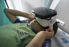 Uzanan erkek çocuk sanal gerçeklik gözlüğü kullanıyor.