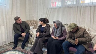 Bir ev ortamında, salonda yan yana oturan dört kişi görülüyor. Koltukta oturanlar ciddi bir sohbet içindeymiş gibi görünüyor. Ortam sade ve düzenli; arka planda tül perdeler, klasik tarzda koltuklar ve desenli bir halı dikkat çekiyor. Atmosfer samimi ve hüzünlü bir ziyaret havası taşıyor.