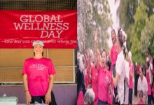 İki kareden oluşan görselde pembe temalı bir etkinlik atmosferi var. Sol tarafta, üzerinde “Global Wellness Day” yazılı pembe tişört giyen bir kadın, aynı ifadeyi taşıyan kırmızı bir pankartın önünde gülümsüyor. Sağ tarafta ise yine pembe tişörtler giymiş kalabalık bir grup açık alanda coşkuyla ellerini kaldırmış; enerjik ve kutlama havasında bir etkinlik anı yansıtılıyor.