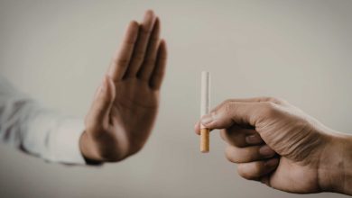 Sade bir arka plan önünde iki el görünüyor. Sağ taraftaki el bir sigara tutarken, sol taraftaki el avuç içi dışa dönük şekilde “dur” işareti yapıyor. Görsel, sigaraya karşı mesafe koymayı ve bırakma mesajını simgeliyor.