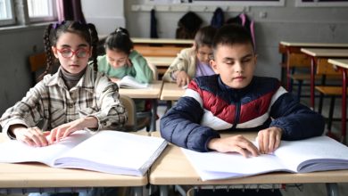 Sıralarda oturan görme engelli erkek ve kız öğrenciler braille yazılı kitapçığa dokunuyor.