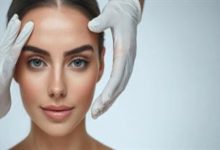 Fotoğrafta, açık renk bir arka plan önünde, doğrudan kameraya bakan genç bir kadının yüzü yakın plandan görülüyor. Kadının cildi pürüzsüz ve aydınlık; kaşları belirgin, gözleri açık renkli. Saçları geriye doğru toplanmış, yüz hatları net biçimde ortaya çıkıyor.