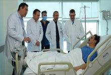 Oyuncu Ufuk Özkan, hastane yatağında uzanıyor ve ameliyatı gerçekleştiren doktorlar ayakta yan yana bulunuyor.