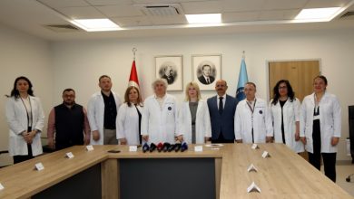 Akdeniz Üniversitesi Rektörü Prof. Dr. Özlenen Özkan ve Organ Nakli Enstitüsü Müdürü Prof. Dr. Ömer Özkan, düzenlenen basın toplantısı odasında diğer hocalar ile beraber poz veriyor.