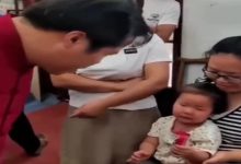 Görselde yer alan yaşlı bir kadının kucağında oturan çocuk ve çocuğunun önünde onu muayene eden doktor yer alıyor.