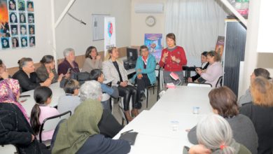Diş Hekimi Nurhan Çelik Demir, masalarda oturan vatandaşlara ayakta durarak konuşma yapıyor.