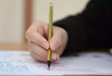 Görselde, bir kişinin sınav optik formu üzerinde kurşun kalemle işaretleme yaptığı yakın plan bir çekim görülüyor. Kalem, cevap alanına doğru tutulmuş ve odak formun üzerindeki işaretleme sürecinde.