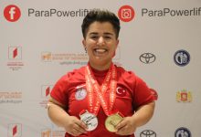 Milli para halterci Besra Duman, boynunda bulunan altın ve gümüş madalyayı tutup gülerek poz veriyor.