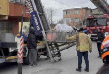 Morbid obezite hastası kadın sepetli vinç içinde bulunuyor. Görevliler ise sokakta ayakta bulunuyor.