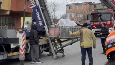 Morbid obezite hastası kadın sepetli vinç içinde bulunuyor. Görevliler ise sokakta ayakta bulunuyor.
