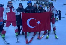 Otizm Kayak Milli Takımımız ve antrenörler Türk bayrağı açarak yarışma alanında poz veriyor.