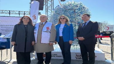 Fotoğrafta açık alanda düzenlenen bir etkinlikte dört kişi yan yana durarak poz veriyor. Arkalarında plastik şişelerden oluşturulmuş büyük bir böbrek maketi yer alıyor. Etkinlik alanında pankartlar ve stantlar bulunurken, ortam böbrek sağlığına dikkat çekmek amacıyla düzenlenen bir farkındalık çalışmasını yansıtıyor.