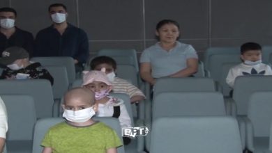 Bir sinema salonunda, çoğu maske takan çocuklar ve yetişkinler koltuklarda oturuyor. Ön sırada saçları dökülmüş, tedavi gördüğü anlaşılan bir çocuk dikkat çekiyor; arka sıralarda ise ona eşlik eden diğer çocuklar ve ebeveynler sakin bir şekilde ekranı izliyor. Atmosfer hem sessiz hem de duygusal bir dayanışma hissi taşıyor.