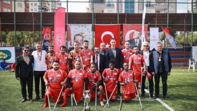 Anadolu Erciyes Engelliler Spor Kulübü sporcuları, yöneticiler kazanılan kupayla sahada poz veriyor.