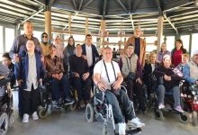 Engelli bireyler, aileleri ve temsilcilerinden oluşan kalabalık bir grup, kapalı bir sosyal alanda toplu fotoğraf çektiriyor. Ön sırada tekerlekli sandalye kullanan katılımcılar yer alırken, arka sırada diğer davetliler bulunuyor. Samimi ve dayanışma dolu bir buluşmanın karesi; birlikte olmanın gücü bazen tek bir fotoğrafa sığar.