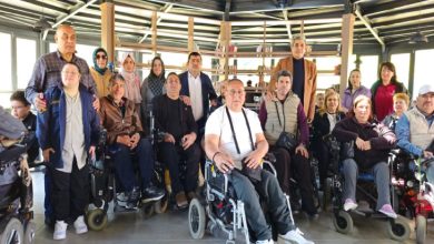 Engelli bireyler, aileleri ve temsilcilerinden oluşan kalabalık bir grup, kapalı bir sosyal alanda toplu fotoğraf çektiriyor. Ön sırada tekerlekli sandalye kullanan katılımcılar yer alırken, arka sırada diğer davetliler bulunuyor. Samimi ve dayanışma dolu bir buluşmanın karesi; birlikte olmanın gücü bazen tek bir fotoğrafa sığar.