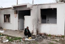 Yıkık ve terk edilmiş bir binanın önünde, etrafı molozlarla kaplı zeminde felçli hasta Mustafa Yıldız, yalnız başına oturuyor.