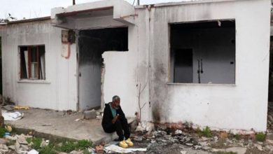 Yıkık ve terk edilmiş bir binanın önünde, etrafı molozlarla kaplı zeminde felçli hasta Mustafa Yıldız, yalnız başına oturuyor.