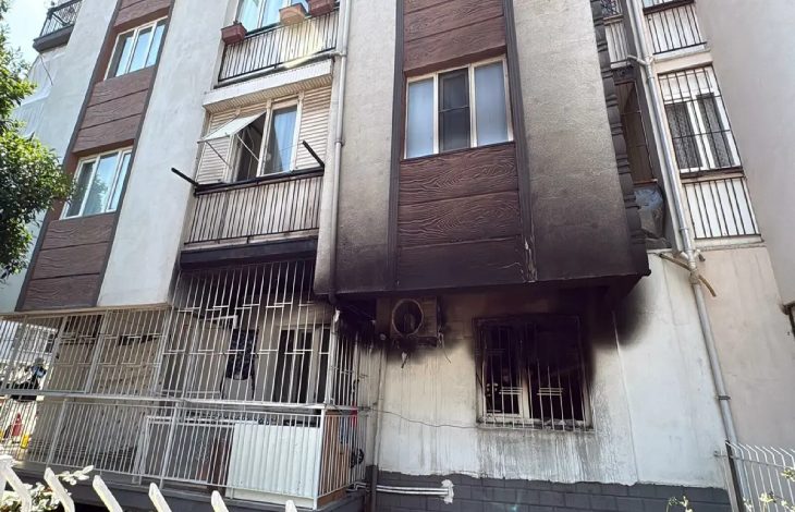 Alt katında yangın çıkmış bir apartmanın dış cephesinde, pencerelerin etrafında yoğun is ve kararma izleri görülüyor.