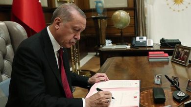 Cumhurbaşkanı Recep Tayyip Erdoğan makamındaki masada oturmuş imza atıyor.