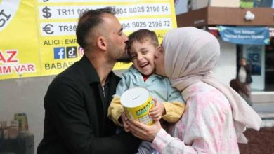 DMD hastası Eymen Altaş'ı babası ve annesi yardım standı önünde öpüyor.