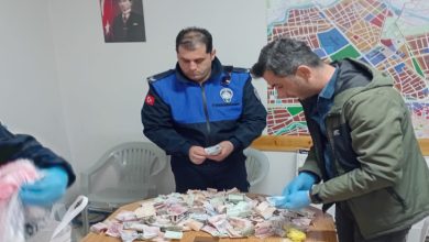 Zabıta memuru iki erkek masa üzerinde bulunan paraları sayıyor.