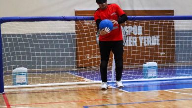 Kale önünde elinde top tutarak ayakta duran erkek goalball sporcusu kadraja yansıyor.