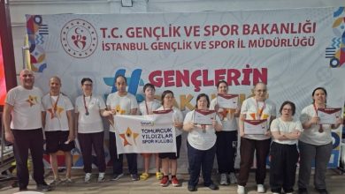 Kapalı bir spor salonunda, “T.C. Gençlik ve Spor Bakanlığı İstanbul Gençlik ve Spor İl Müdürlüğü” yazılı bir pankart önünde bir grup sporcu yan yana duruyor. Üzerlerinde beyaz tişörtler olan sporcuların bazılarının boynunda madalyalar var, bazıları da ellerinde katılım belgeleri tutuyor. Ortada bir ekip, “Tomurcuk Yıldızlar Spor Kulübü” yazılı pankart açmış. Genel atmosfer, bir yarışma sonrası toplu fotoğraf ve başarı anı hissi veriyor.