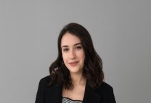 Gri arka plan önünde çekilmiş portre fotoğrafta, koyu renk ceket giyen genç bir kadın kameraya hafif bir tebessümle bakıyor. Sade ve profesyonel kadraj, akademik ya da kurumsal bir profil fotoğrafı havası taşıyor.