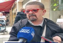 Sokakta yapılan bir röportajda, kırmızı çerçeveli gözlük takan bir adam mikrofonlara konuşuyor. Önünde “Kanal Ordu” yazılı bir mikrofon tutulurken, yanında bir telefon da kayıtta. Arka planda kafe ve yaya trafiği görülüyor; sahne gündelik bir sokak röportajını yansıtıyor.