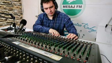 Radyocu Muhammed Emirhan Güngör, kulaklık takmış radyo stüdyosunda büyük bir ses mikseri üzerinde dikkatle ayar yaparken görülüyor.