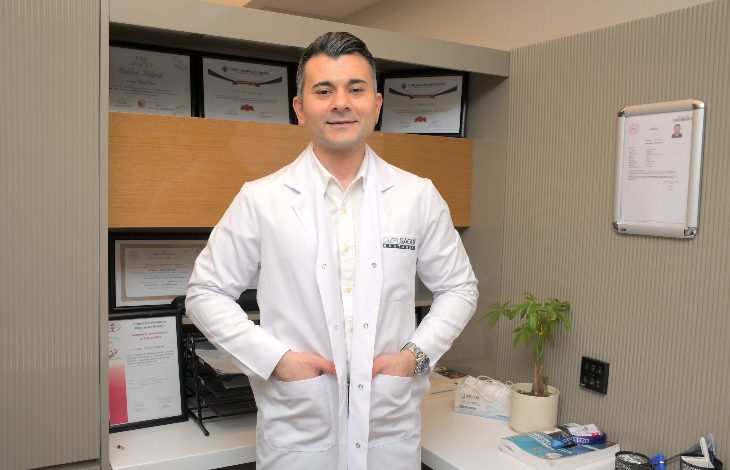 Görselde, Özel Sağlık Hastanesi Fizik Tedavi ve Rehabilitasyon Uzmanı Dr. Arman Öztürk ayakta duruyor ve elleri üniformasının cebinde.