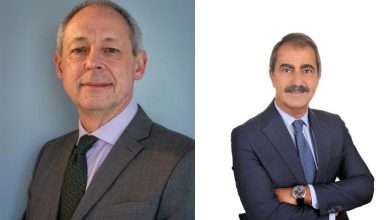 Görselde yan yana yerleştirilmiş iki erkek portresi bulunuyor. Soldaki kişi açık renk bir arka plan önünde, gri takım elbise ve yeşil tonlarında kravatla poz vermiş. Saçları seyrek ve kısa, yüzünde sakin ve ciddi bir ifade var. Doğrudan kameraya bakıyor ve daha klasik, resmi bir duruş sergiliyor. Sağdaki kişi ise beyaz arka plan önünde, koyu renk takım elbise ve kravatla, kollarını çapraz yapmış şekilde duruyor. Gür bıyığı ve daha belirgin yüz hatları dikkat çekiyor. Pozu daha kendinden emin ve güçlü bir duruş yansıtıyor.