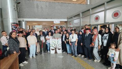Adliye binası içinde düzenlenen etkinlikte özel gereksinimli bireyler, aileleri ve adliye personeli toplu halde bir araya gelerek fotoğraf çektiriyor. Ortada “adalet ağacı” temalı pano yer alırken, etkinlik yoğun katılım ve dayanışma atmosferiyle dikkat çekiyor.
