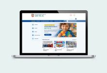 Açık gri arka plan üzerinde yer alan dizüstü bilgisayar ekranında, otizm farkındalığına yönelik hazırlanmış bir internet platformunun ana sayfası görülüyor. Ekranda puzzle parçası tutan bir çocuk fotoğrafı, bilgilendirme menüleri ve duyuru alanları yer alıyor.