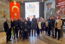 Kalabalık bir grup, kapalı bir alanda yan yana dizilerek kamera karşısında poz veriyor. Arka planda Türk bayrağı ve “Engelsiz Ankara Festivali”ne ait afişler yer alıyor. Grup içinde tekerlekli sandalyede bulunan bireyler ve beyaz baston kullanan kişiler de dikkat çekiyor. Görüntü, engelli bireylerin katılımıyla gerçekleşen bir etkinlik ya da basın açıklaması öncesi toplu fotoğraf anını yansıtıyor.